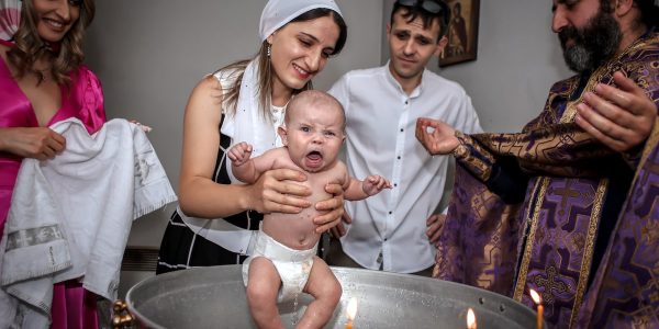 A touching baptism ceremony with a family and priest, capturing joyful expressions.