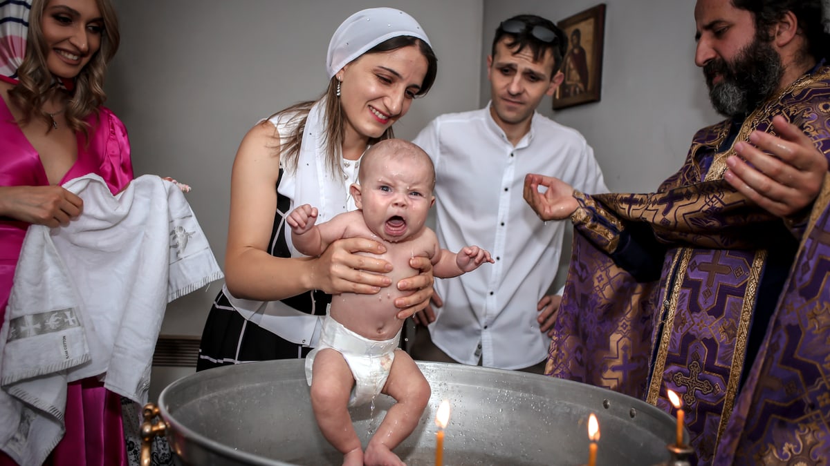 A touching baptism ceremony with a family and priest, capturing joyful expressions.