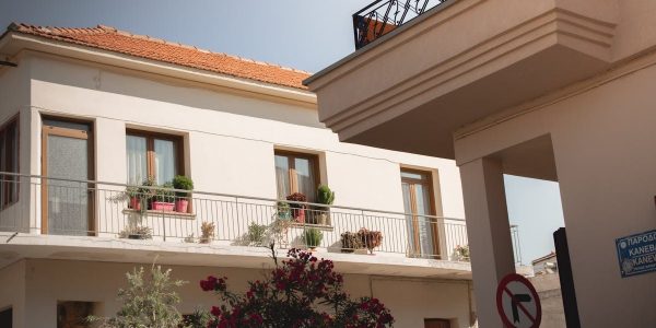 Traditional Greek house facade with potted plants and balcony details.